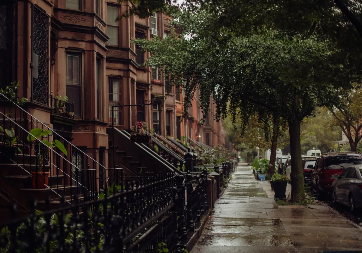 Quaint urban street view of brownstone homes on a rainy New York day.