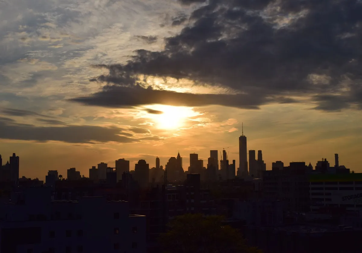 Silhouette of the New York City skyline against a vibrant sunset sky.