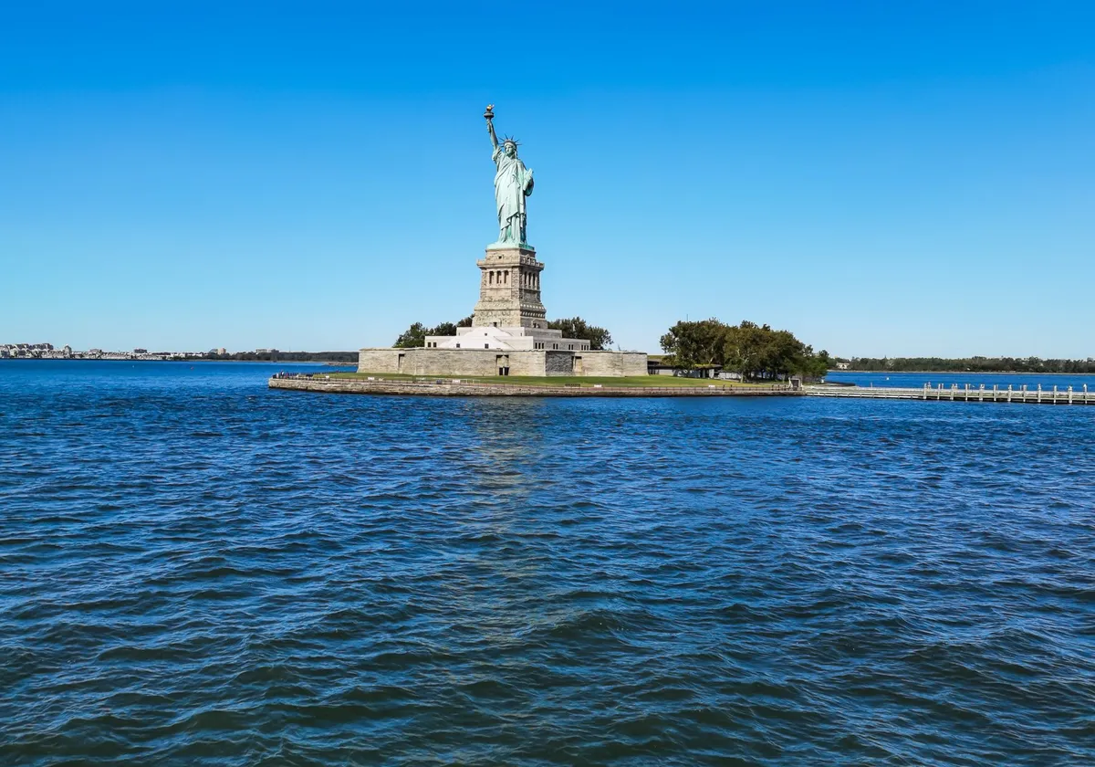 Iconic view of the Statue of Liberty on Liberty Island, New York, under a clear blue sky.